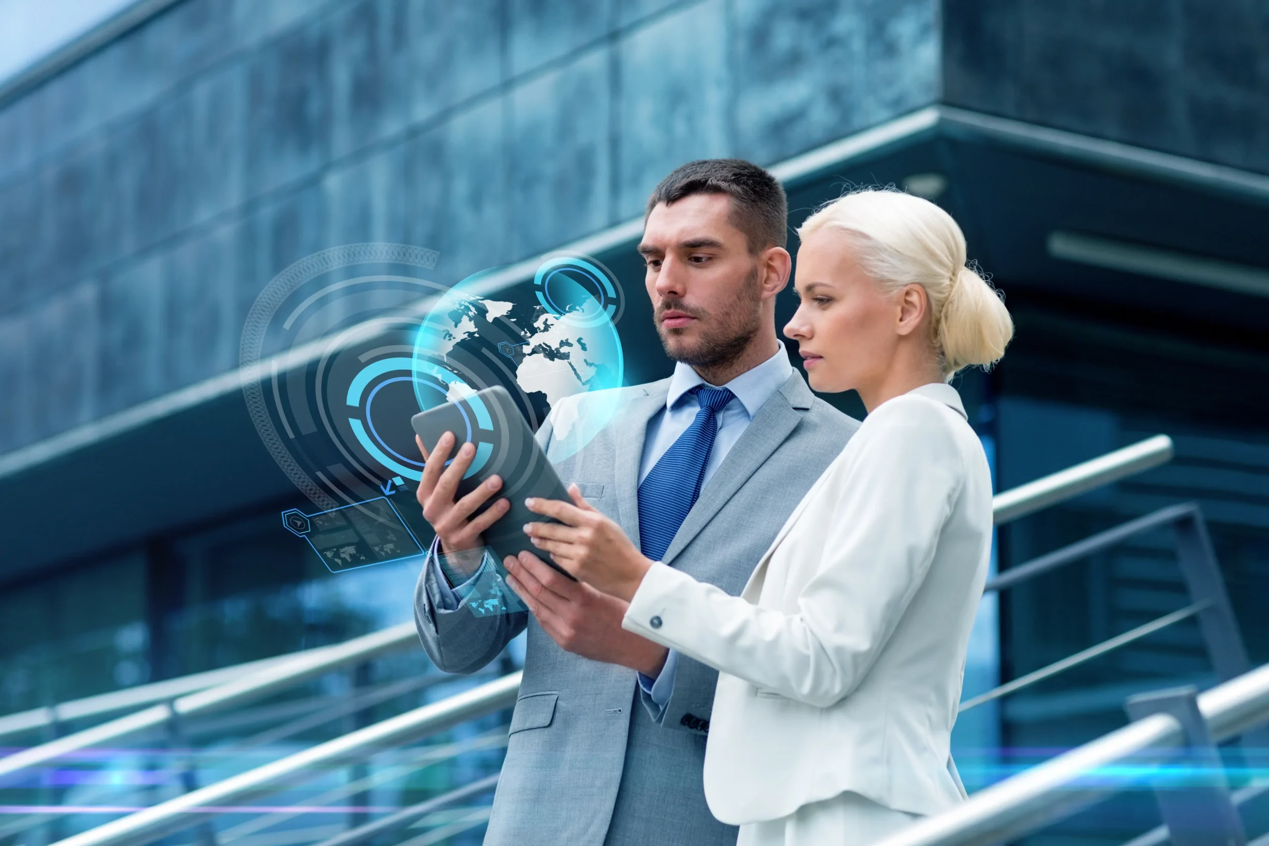 Two business professionals reviewing data on a digital tablet with futuristic HUD graphics, illustrating the future of executive assistant roles in an AI‑first world.