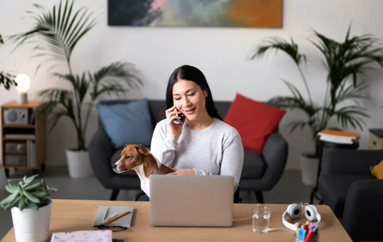 Executive assistant for real estate founders working remotely on laptop while managing phone calls and property coordination