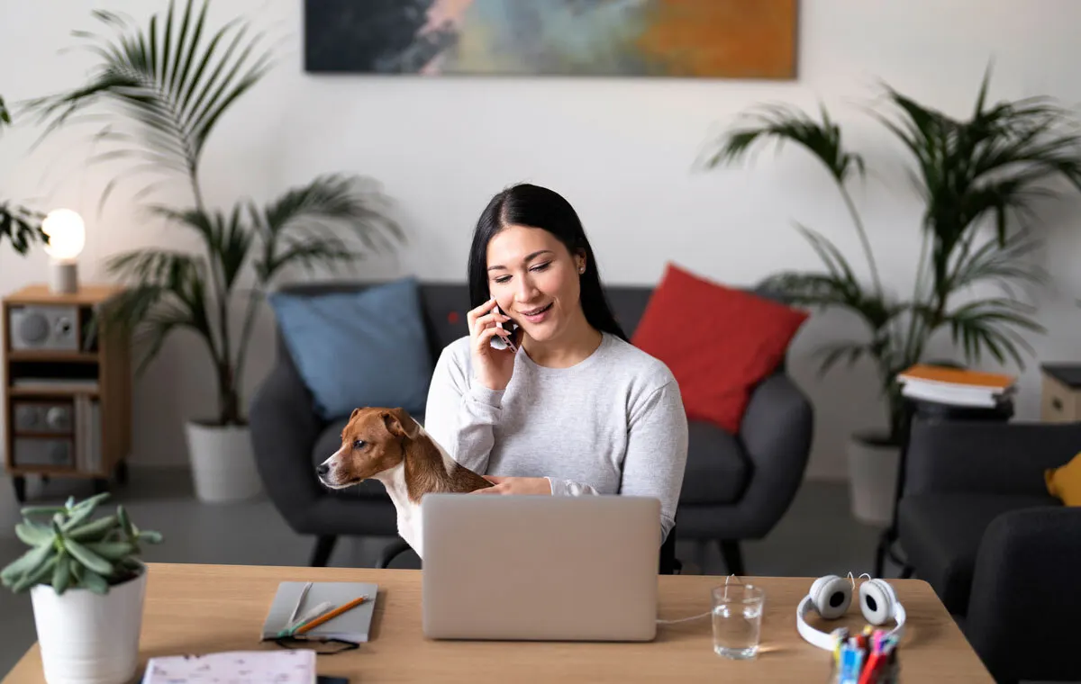 Executive assistant for real estate founders working remotely on laptop while managing phone calls and property coordination
