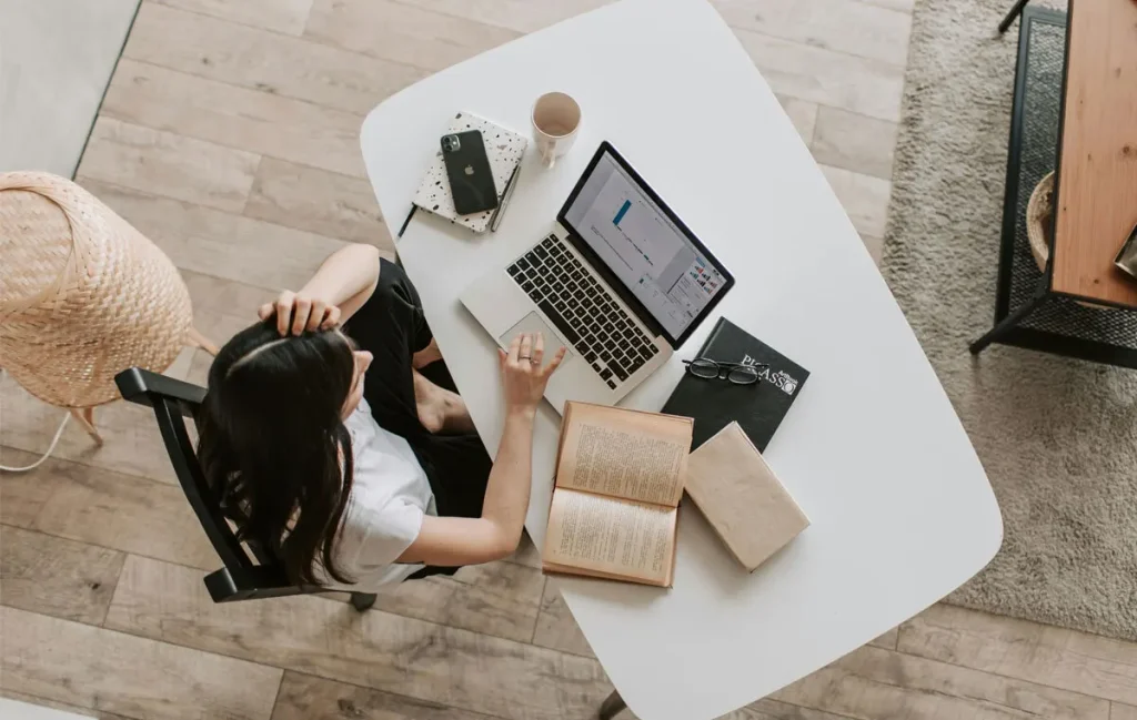 Executive assistant working remotely from home office with laptop and organized workspace