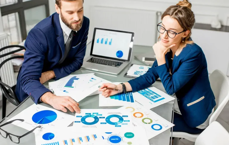 Professional executive assistants reviewing business reports and analytics together, illustrating executive assistant roles and responsibilities in corporate planning.