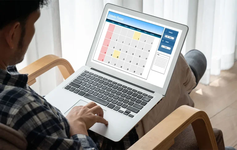 Professional marketing executive assistants managing digital calendar on laptop showing strategic time blocking and meeting optimization