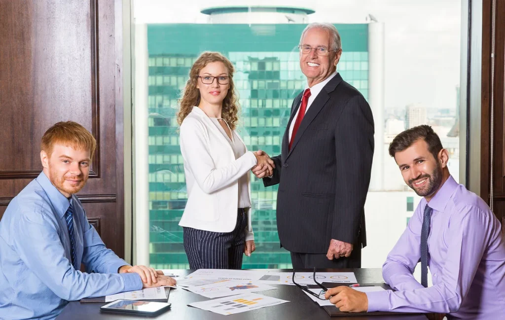 Executives shaking hands after finalizing a deal with offshore development companies for IT outsourcing services.